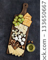 Gourmet cheese platter with crackers, grapes, walnuts, and honey on rustic dark background 133650667