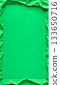 Crumpled green paper frame with empty center on solid background. Abstract textured border with copy space for design and layout. 133650716