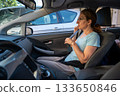 Berlin, Germany August 10, 2023. Car safety concept: A middle-aged woman is fastening her seat belt before the car starts. 133650846