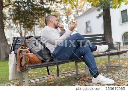 Man enjoying snack in park, taking a break outdoors 133650965