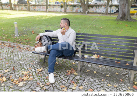 Man enjoying snack in park during autumn season 133650966