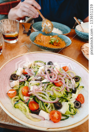 a bowl of spiralized cucumber salad on a table 133651159