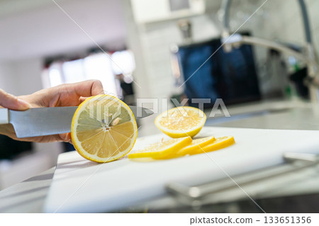 Woman cutting lemon into slices Woman cutting lemon into slices 133651356