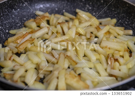 Potatoes cut into slices are deliciously fried in a frying pan. Potatoes cut into slices are deliciously fried in a frying pan. 133651902