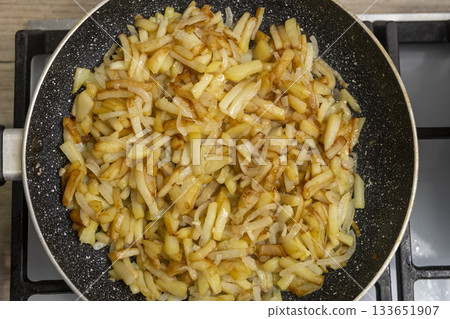 Sliced potatoes with onions are deliciously fried in a frying pan. Sliced potatoes with onions are deliciously fried in a frying pan. 133651907