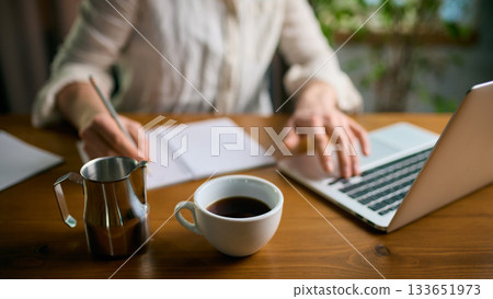 Coffee and metal pitcher on office desk during active work Coffee and metal pitcher on office desk during active work 133651973