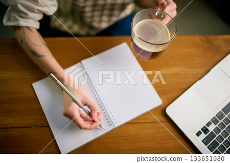 Hand holding coffee above notebook during focused office work Hand holding coffee above notebook during focused office work 133651980