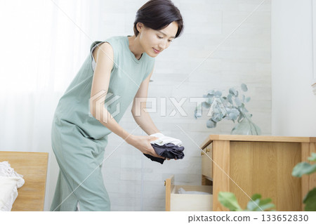 A woman putting clothes away in a dresser A woman putting clothes away in a dresser 133652830