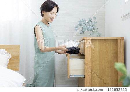 A woman putting clothes away in a dresser A woman putting clothes away in a dresser 133652833