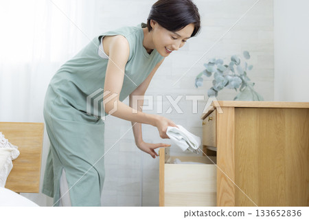 A woman putting clothes away in a dresser A woman putting clothes away in a dresser 133652836