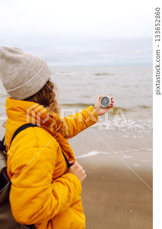 Woman traveler looking for directions with a compass on beach. Active lifestyle. Adventure concept. Woman traveler looking for directions with a compass on beach. Active lifestyle. Adventure concept. 133652860