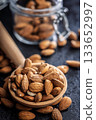 Almond kernel nuts on wooden spoon on black table. 133652997