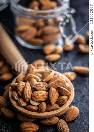 Almond kernel nuts on wooden spoon on black table. Almond kernel nuts on wooden spoon on black table. 133652997