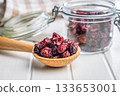 Tasty dried cranberries on spoon on white table. 133653001
