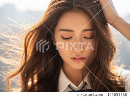 美麗的女子沐浴在柔和的陽光下，秀髮隨風飄揚。 133653586