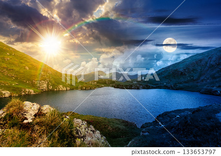 beautiful scenery with alpine lake. day and night time change concept. gorgeous clouds over the distant mountain ridge with sun and moon. steep grassy slopes with rocks. equality and shift template beautiful scenery with alpine lake. day and night time change concept. gorgeous clouds over the distant mountain ridge with sun and moon. steep grassy slopes with rocks. equality and shift template 133653797