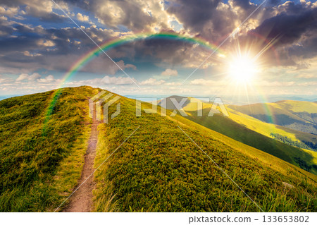 path uphill the mountain top at sunset. beautiful summer scenery with dynamic clouds on a blue sky in evening light. scenic landscape with rolling hills. storytelling cinematic image under the rainbow path uphill the mountain top at sunset. beautiful summer scenery with dynamic clouds on a blue sky in evening light. scenic landscape with rolling hills. storytelling cinematic image under the rainbow 133653802