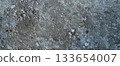 Close-up of a gray-black lava texture on the ground. Porous, cracked, and stony, perfect as a stock texture or photo background. Impression of molten rock. 133654007