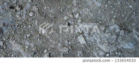 Close-up of a gray-black lava texture on the ground. Porous, cracked, and stony, perfect as a stock texture or photo background. Impression of molten rock. 133654010