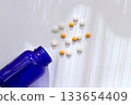 Healthcare image of pills and blue bottles spread out on white background 133654409