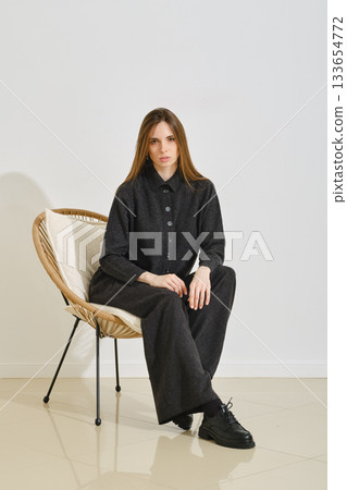 A model sits in a stylish chair, wearing a trendy black outfit that emphasizes both practicality and comfort 133654772