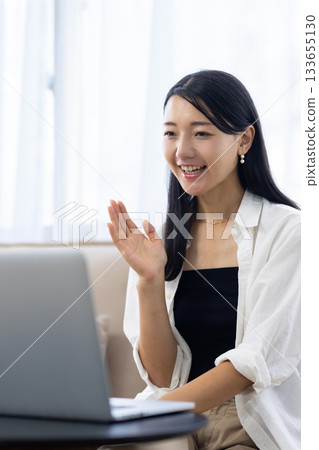 Young woman making a video call on a laptop in the living room at home 133655130