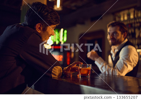 Man chatting with bartender while resting cocktail on bar counter Man chatting with bartender while resting cocktail on bar counter 133655207