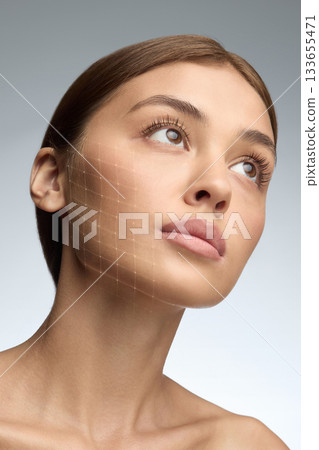 Woman with digital mesh highlight on cheek looking upward in clean beauty studio Woman with digital mesh highlight on cheek looking upward in clean beauty studio 133655471