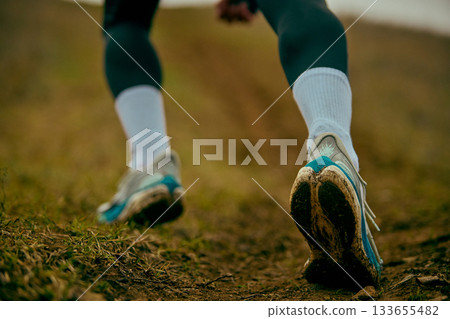 Running shoes pushing off muddy ground during hill climb 133655482