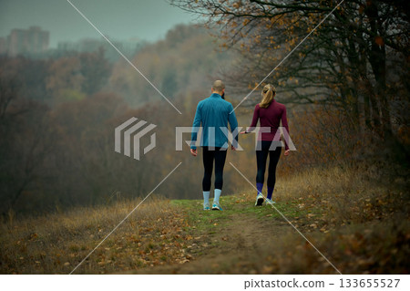 Couple walking cool-down path in misty autumn forest after trail run Couple walking cool-down path in misty autumn forest after trail run 133655527