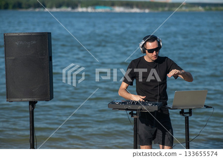 Male DJ playing music on the beach.  133655574