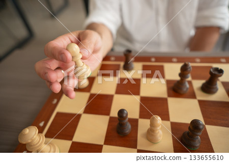 Close up of hands of middle aged caucasian man playing chess. Close up of hands of middle aged caucasian man playing chess. 133655610