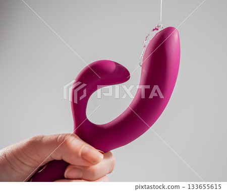 Lube pouring on pink dildo on white background. Lube pouring on pink dildo on white background. 133655615