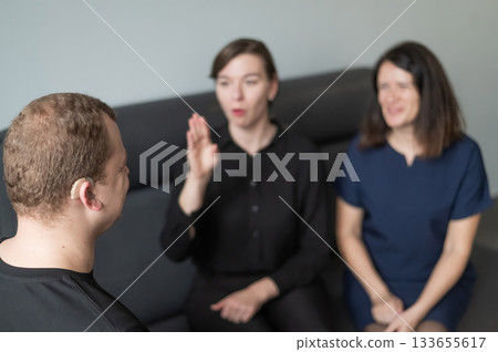 A man and two women are talking in Russian sign language.  133655617