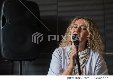 Caucasian woman singing into microphone in music studio.  133655632