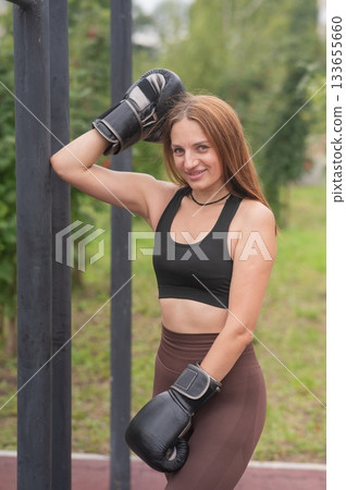 A Caucasian woman poses in boxing gloves on a sports field. A Caucasian woman poses in boxing gloves on a sports field. 133655660