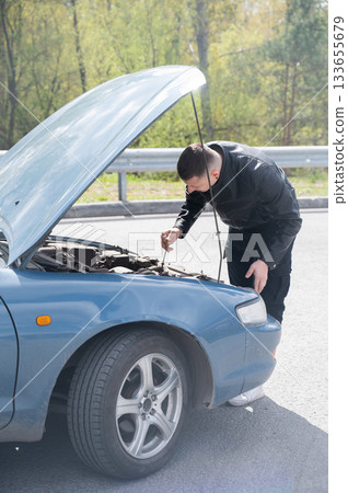 Caucasian man checking engine oil level in his car. Caucasian man checking engine oil level in his car. 133655679