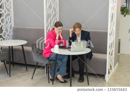 Colleagues are sitting at a laptop and discussing work.  133655683