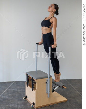 Caucasian woman doing Pilates on classic chair. Caucasian woman doing Pilates on classic chair. 133655764