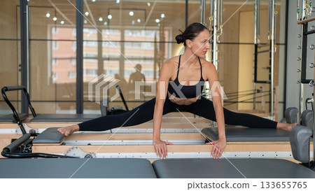 Caucasian woman doing side splits on reformer.  133655765