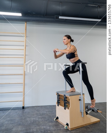 Caucasian woman doing Pilates on classic chair. Caucasian woman doing Pilates on classic chair. 133655766