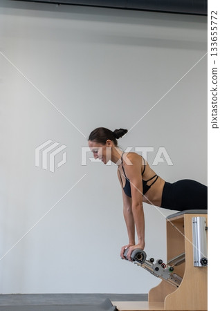 Caucasian woman doing Pilates on classic chair. 133655772