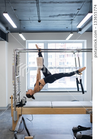 Caucasian woman doing pilates on reformer. Caucasian woman doing pilates on reformer. 133655774