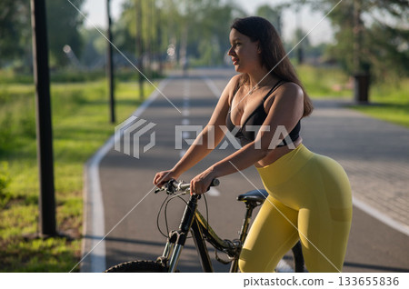 Curvy Caucasian Woman Riding Bicycle in Park.  133655836
