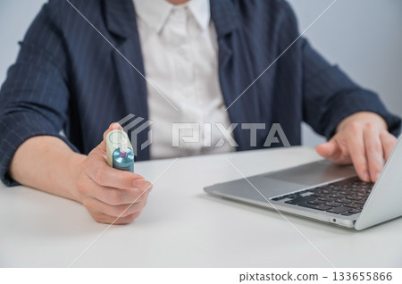 Business woman smoking an electronic cigarette while working on a laptop. Tobacco heating system. Business woman smoking an electronic cigarette while working on a laptop. Tobacco heating system. 133655866