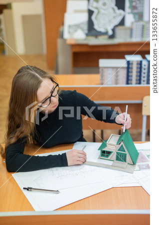 Caucasian young woman making a model of a building. Student of the construction university.  133655872