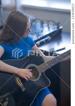 Young woman playing guitar in recording studio.  133656017