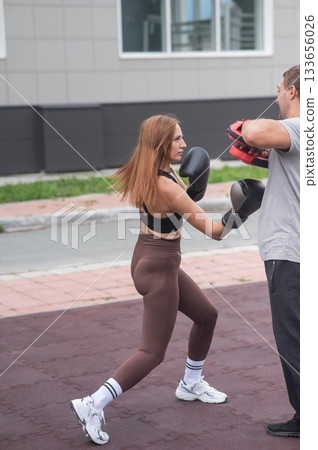 Man and woman sparring outdoors. Boxing lesson. Man and woman sparring outdoors. Boxing lesson. 133656026