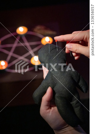 Woman sticking pins into voodoo doll.  133656057
