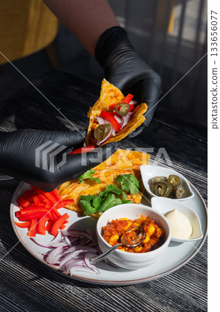 A chef wearing black gloves prepares fajitas. A chef wearing black gloves prepares fajitas. 133656077